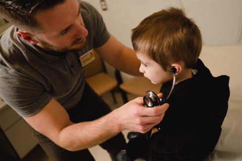 Family doctor places stethoscope on child's ears